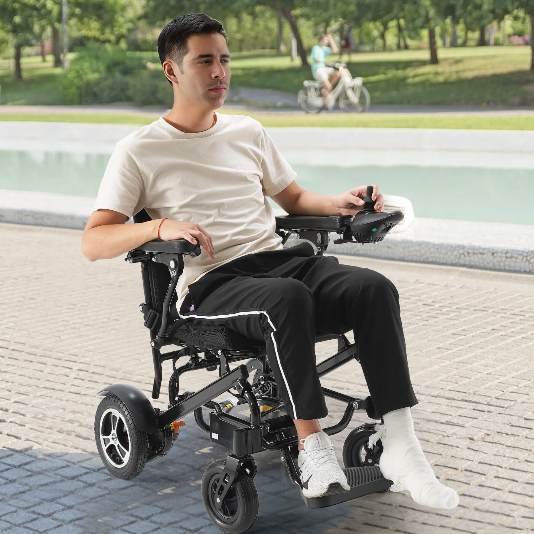 A man recovering from a foot injury is using a power wheelchair to relax outside.