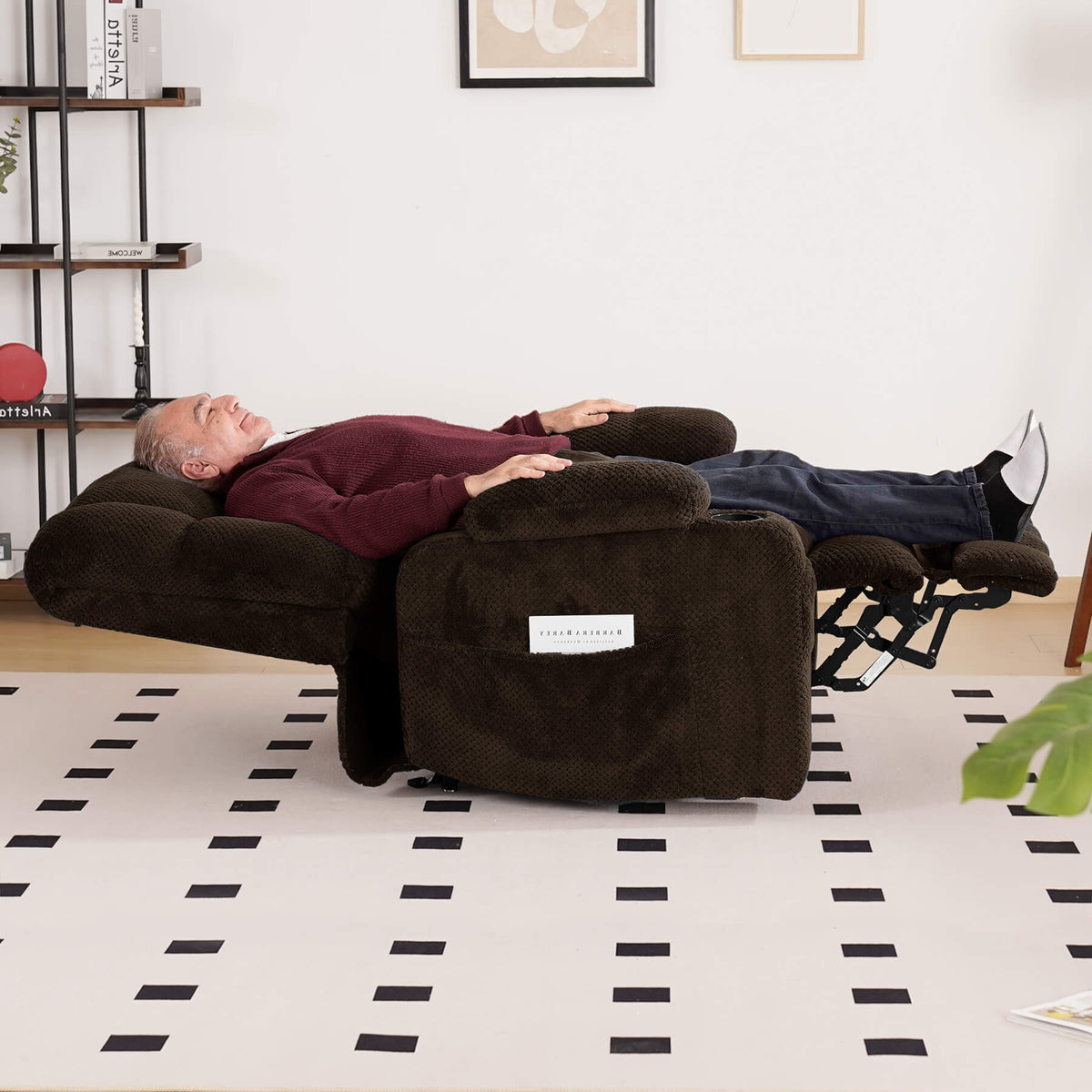 A person is sleeping on a brown lie-flat recliner in the living room.