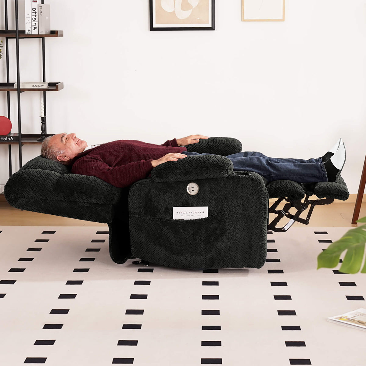 A person is sleeping on a gray lie-flat recliner in the living room.